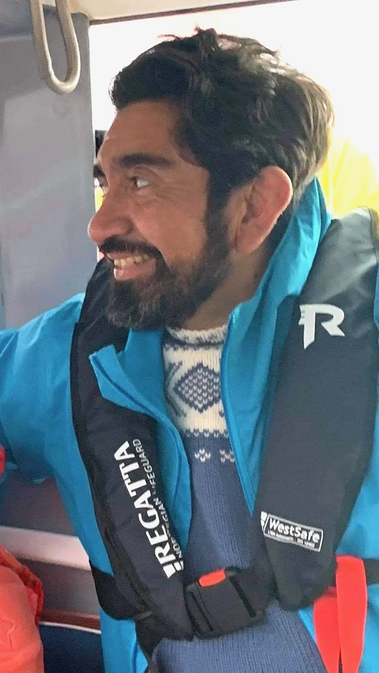 Cristian smiling in a life jacket on board a boat, summer 2021